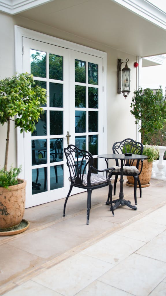 Charming outdoor patio with wrought iron furniture and French doors, perfect for relaxation.