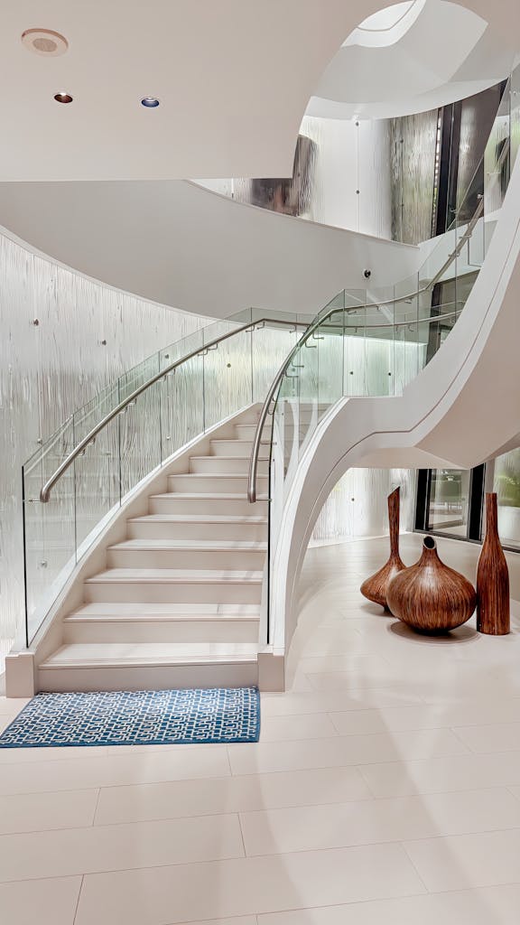 Stunning spiral staircase with glass railing in a luxurious Abu Dhabi home interior.